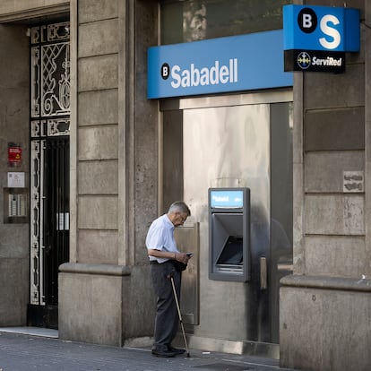 Un anciano saca dinero del cajero en una oficiana del Banc Sabadell de la Gran Vía. 