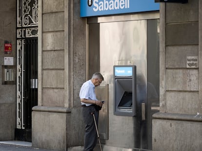Un anciano saca dinero del cajero en una oficiana del Banc Sabadell de la Gran Vía.