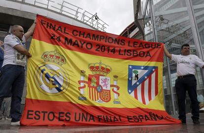 Dos aficionados del Real Madrid sostienen una bandera en el exterior del estadio de La Luz, donde mañana se disputará la final de la Liga de Campeones.
