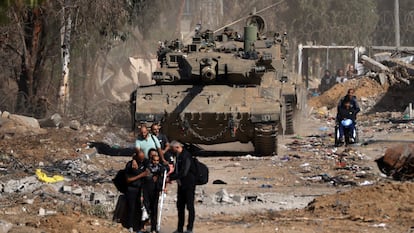 Ciudadanos palestinos, algunos heridos, pasaban junto a un tanque israelí en su huida hacia el sur de la Franja, en las afueras de la ciudad de Gaza, el viernes.