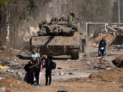 Ciudadanos palestinos, algunos heridos, pasaban junto a un tanque israelí en su huida hacia el sur de la Franja, en las afueras de la ciudad de Gaza, el viernes.