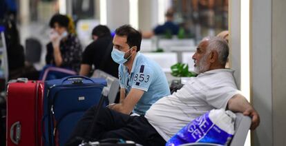 Viajeros esperan sentados con sus maletas en el Aeropuerto Internacional de Bagdad (Irak). 