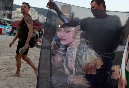 Un hombre vende mercancías de Madonna mientras la gente se reúne en la playa de Copacabana.