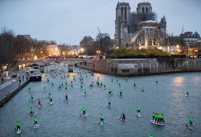 Aficionados y profesionales de paddle surf navegan por el río Sena a su paso por la catedral de Notre Dame (París), el 8 de diciembre.