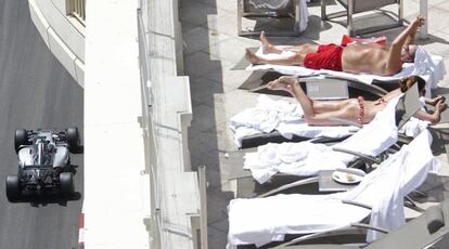 Una pareja tomando el sol en una azotea mientras pasa el piloto británico Lewis Hamilton, durante una sesión de clasificación del GP de Mónaco.