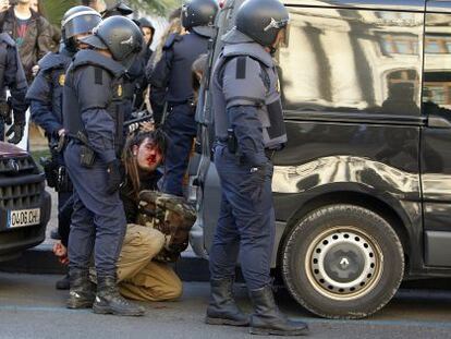 A bloodied protestor is detained by police in Valencia on Monday.