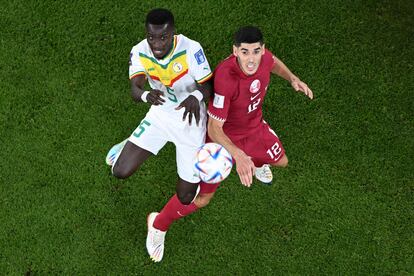 El mediocentro senegalés Idrissa Gana Gueye (izquierda) pelea un balón con el centrocampista catarí  Karim Boudiaf (derecha) en el estadio Al-Thumama de Doha (Catar).
