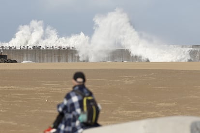 Un hombre observa las olas que este lunes han rebasado el rompeolas de la playa de Plentzia (Bizkaia).