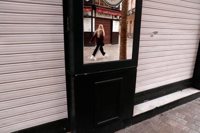 Una persona se refleja en el espejo de la fachada de un comercio cerrado este jueves en el centro de Málaga.