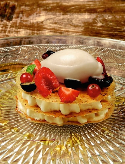 <p><b>Ingredientes: </b> 4 bolas hermosas de sorbete de mango, 100 gramos de nata, 200 gramos de mascarpone, 20 hebras de azafrán, 100 gramos de caramelos de sabor neutro, 50 gramos de azúcar, 30 gramos de agua. <p><b>Preparación</b> 1. Montar las cantidades de nata y mascarpone con la varilla hasta que comiencen a tomar cuerpo. Añadir azúcar hasta que se disuelva bien (ha de quedar con suficiente cuerpo para tirar con manga pastelera). Reservar en frío. 2. Cocer el azúcar y el agua hasta que comience a tomar punto, entonces volcar sobre el azafrán y reservar en frío. 3. Triturar los caramelos con un robot hasta obtener un polvo fino. 4. Poner una bandeja de horno con silpat y espolvorear el polvo de caramelo en forma de círculos. Cocer en el horno a 170º durante 6 minutos, el caramelo se fundirá y nos dejará unas capas muy delicadas. 5. Poner en un plato una capa de caramelo; alrededor, la crema de mascarpone, y en el centro, un poco de sorbete. Cubrir con otra capa de caramelo y repetir la operación. Cubrir otra vez y ponemos una quenelle de sorbete de mango y frutas variadas. 6. Salsear con el jarabe de azafrán.