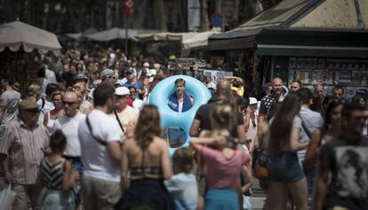 Un turista amb flotador i tovallola a l'espatlla baixa per les Rambles.