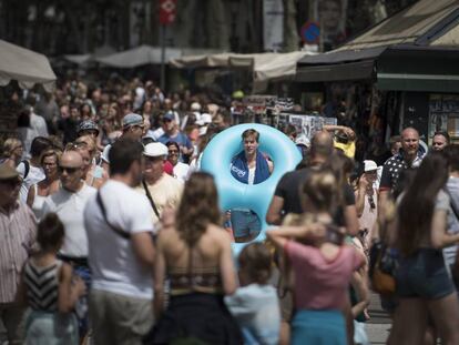 Un turista amb flotador i tovallola a l'espatlla baixa per les Rambles.