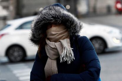 Una mujer se protege del frío a primera hora la mañana en una céntrica calle de Madrid.