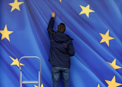 Un operario pega con adhesivo la bandera de la Unión Europea en la entrada de la sede de la Comisión, en Bruselas (Bélgica).