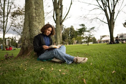 Una joven lee en un parque.