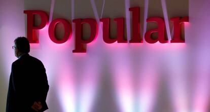 Un hombre pasa ante un cartel del Banco Popular en la presentación de resultados