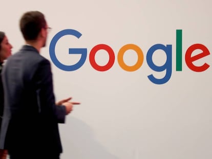 Duas pessoas passam junto ao logotipo do Google em Paris.