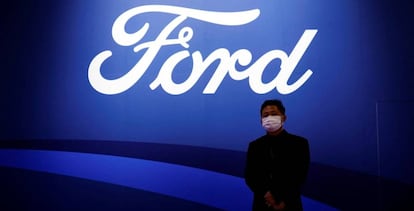 Un hombre posa frente al logo de la marca Ford en el salón del automóvil de Shanghái.