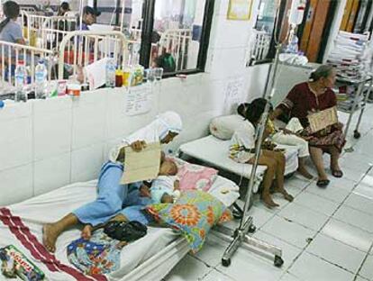 Varios pacientes afectados por el virus del dengue reciben tratamiento en el pasillo de un hospital de Yakarta.