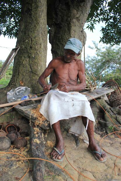 O quilombola Domingos Humberto de Oliveira, de 73 anos, trabalha o ambé, um tipo de cipó que serve para tecer o paneiro, uma espécie de mochila cilíndrica usada pelos quilombolas para colher castanha, ao fundo à direita da imagem. Aos seus pés, ouriços abertos, de onde se tira a castanha-do-pará.