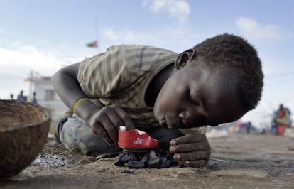 Un niño del distrito de Buzi, a 200 kilómetros de Beira (Mozambique), la zona arrasada por el paso del ciclón Idai hace una semana, intenta encender un fuego con restos de carbón para calentar algo de comida en una lata.