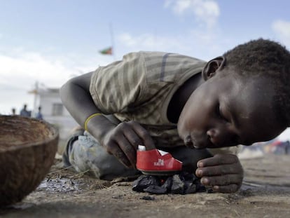 Un niño del distrito de Buzi, a 200 kilómetros de Beira (Mozambique), la zona arrasada por el paso del ciclón Idai hace una semana, intenta encender un fuego con restos de carbón para calentar algo de comida en una lata.