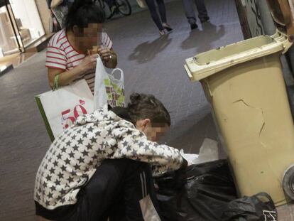 Dos personas buscando comida en unos contenedores de basura. 