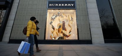 Dos personas pasan frente a un escaparate de Burberry en Pek&iacute;n (China).