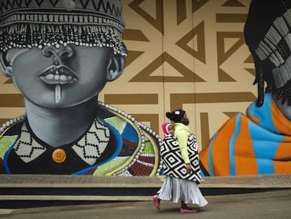 Una madre pasea con su hijo junto a unos grafitis en las calles de Johanesburgo (Sudáfrica). 