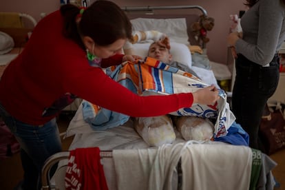 Lidiya Gladun levanta la sábana para revisar los vendajes en las piernas amputadas de su hijo en el Third City Hospital, en Cherkasi,  el viernes 6 de mayo de 2022. 