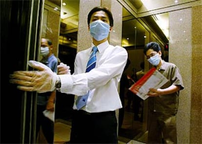 Un ascensorista provisto con mascarilla y guantes trabaja en un centro comercial en Hong Kong.
