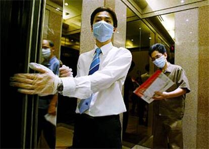 Un ascensorista provisto con mascarilla y guantes trabaja en un centro comercial en Hong Kong.