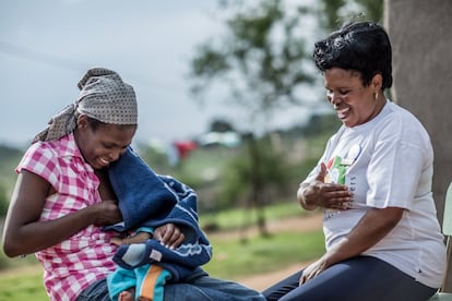 Nokuthula Hung, de 27 años, vive en Everson Village, Amsterdam, Sudáfrica. Debido a que Nokuthula es VIH positiva, tuvo miedo al descubrir que estaba embarazada, pero como continuó su tratamiento antirretroviral y amamantó exclusivamente a su hijo Knowledge, que en el momento de la fotografía tenía tres meses, Nokuthula espera que su hijo crezca libre de VIH. En la imagen, una Madre Mentora instruye a Nokuthula sobre cómo dar el pecho correctamente.