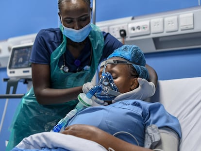 La enfermera de cuidados intensivos, Emily Chepng'eno (izquierda) coloca una máscara de ventilación mecánica durante una simulación para demostrar su funcionamiento tras la instalación de una moderna planta de oxígeno en el Hospital Metropolitano de la capital de Kenia, Nairobi, el 5 de mayo de 2021.