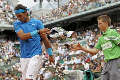 Rafael Nadal devuelve su toalla a un recogepelotas y se dispone a reiniciar el juego.
