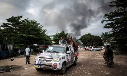 Un automóvil con propaganda electoral cerca de un incendio en un almacén de máquinas para votar, este jueves en Kinshasa.