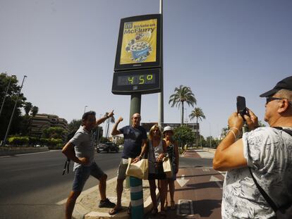 Unos turistas se fotografían debajo de un termómetro de calle que marca 45 grados, este jueves en Córdoba.