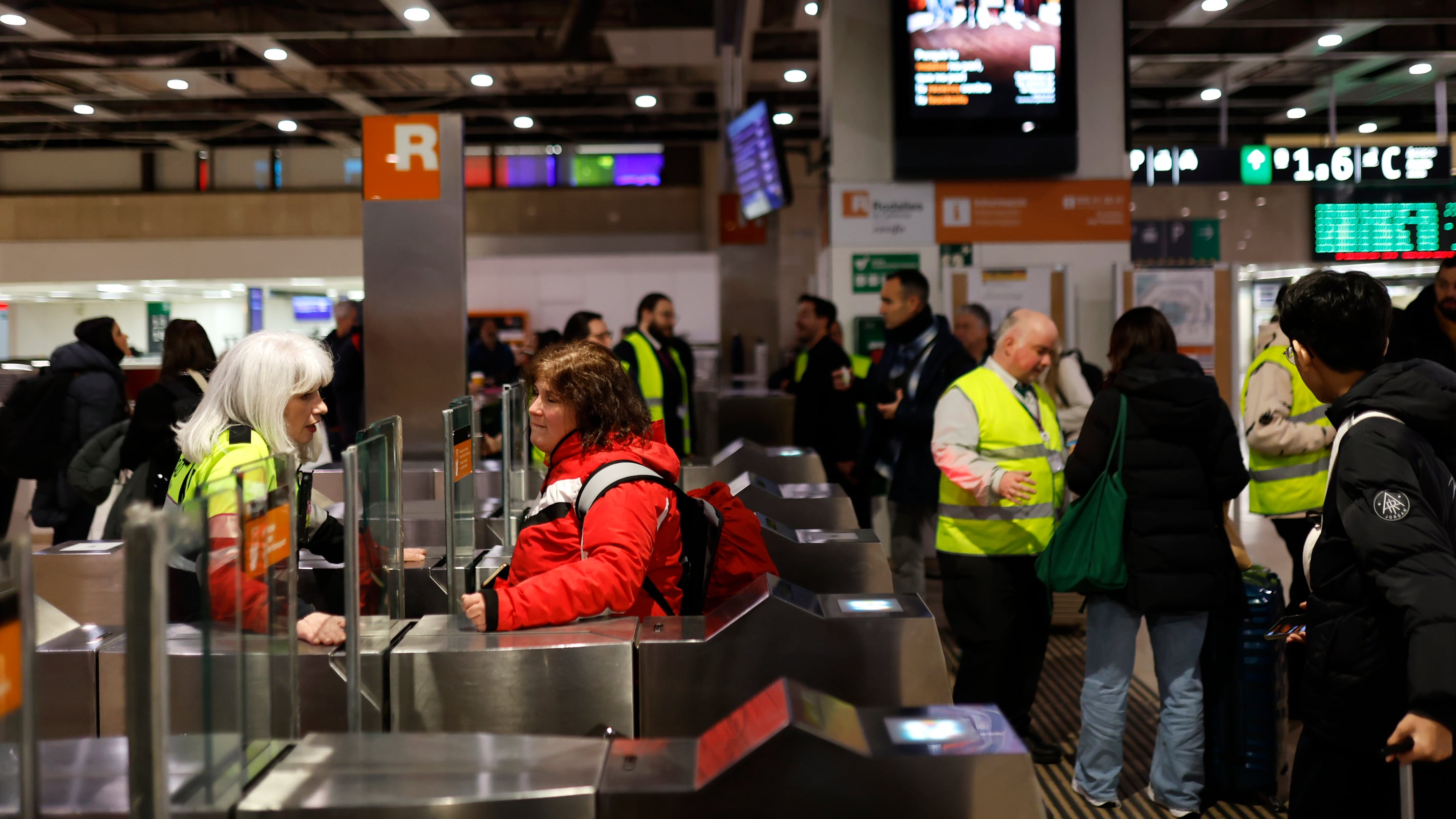 Informadores de la estación de Sants comunican a varios pasajeros que está cerrado el servicio de Rodalies, este sábado.