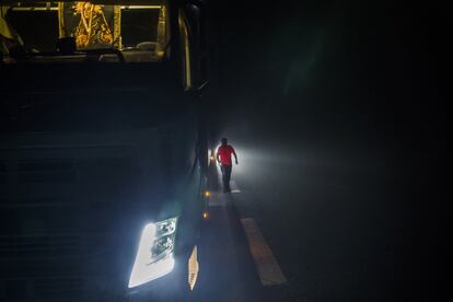 Lázaro comprueba entre la niebla el estado de su camión antes de emprender la ruta, la madrugada del 16 de octubre. Ha tenido que pasar la noche en un apartadero de la carretera porque no encontró un área de servicio disponible.