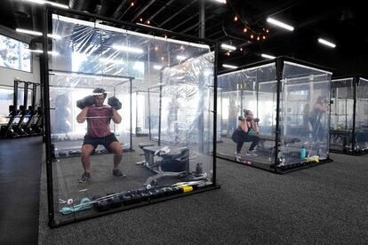 Varias personas hacen ejercicio en cubículos individuales, en un gimnasio de Redondo Beach (California, Estados Unidos).