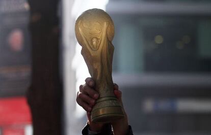 Un aficionado sostiene una r&eacute;plica de la Copa del Mundo.