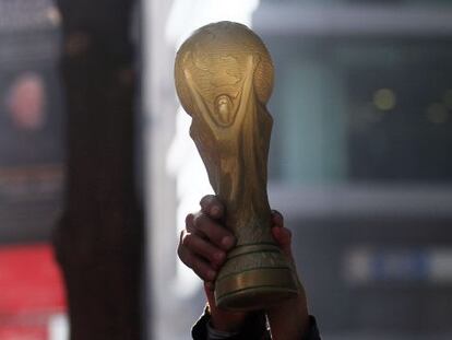 Um torcedor segura uma réplica da Copa do Mundo.