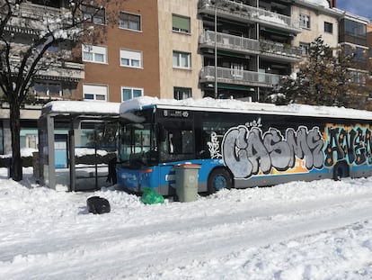 Un autobús de la EMT, atrapado en la nieve y con pintadas en una calle de Madrid.