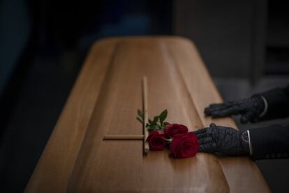 Un trabajador de una funeraria prepara un féretro de una víctima de covid antes de su incineración, en un tanatorio de la empresa Mémora, en Girona.