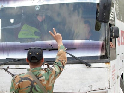 Soldados sírios fazem o símbolo da vitória em frente a um ônibus que evacua rebeldes em Duma, nos arredores de Damasco.