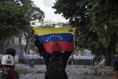 Un manifestante levanta una bandera venezolana en frente de miembros de la Guardia Nacional Bolivariana (GNB).
