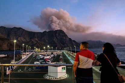 Two people in the port ofAgaete watch smoke rise from Pinar de Tamadaba.