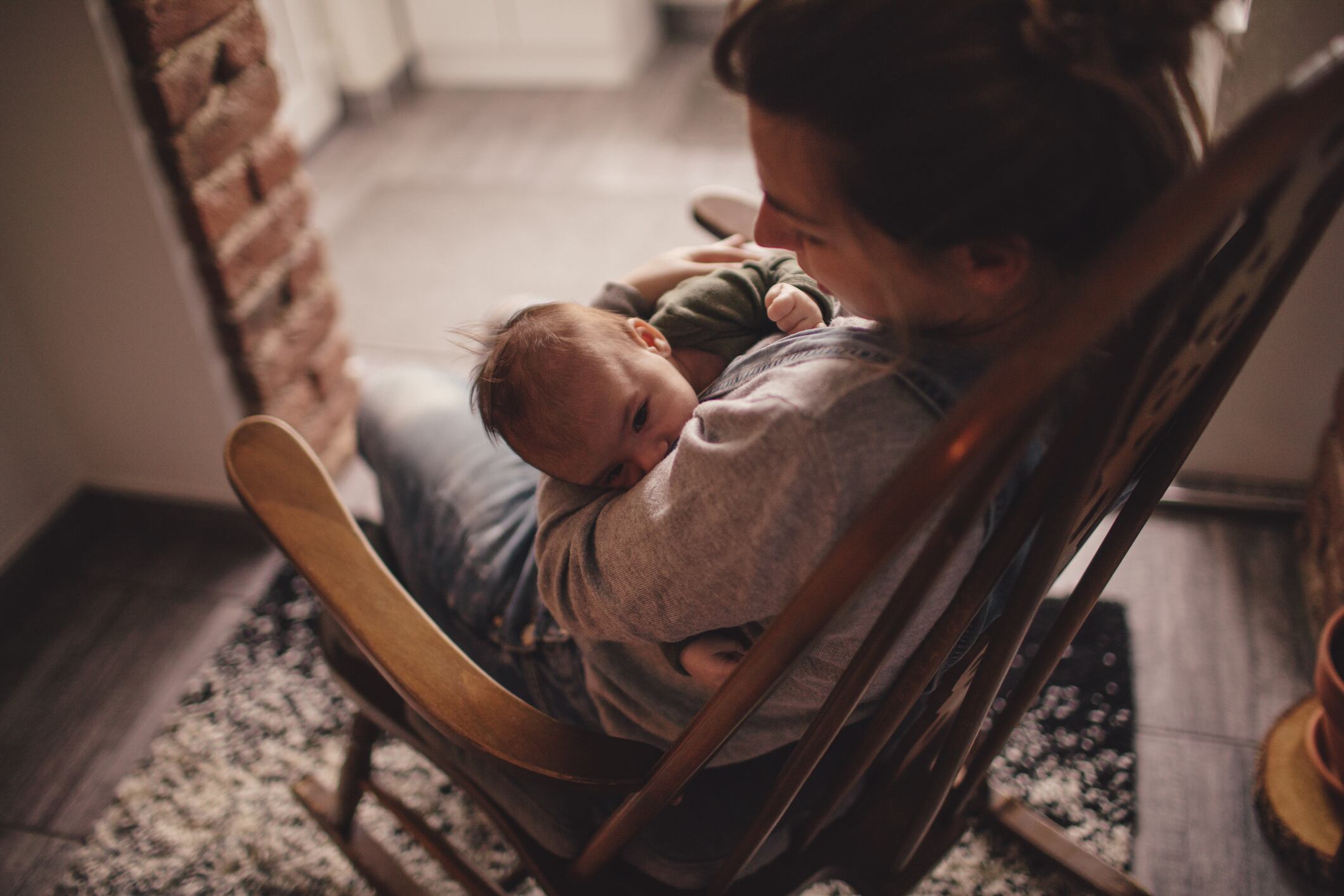 Una madre mece a su hijo en una silla. 