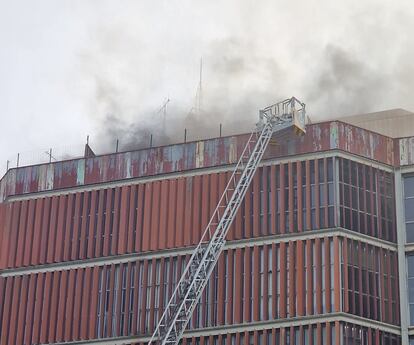 Los bomberos intentan sacar empleados del edificio durante el incendio.