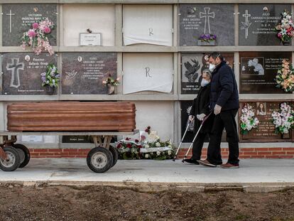 Un operario traslada un féretro seguido por los familiares de la víctima durante un entierro, en Valencia.